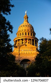 Silhouettes Of Trees Frame The Granite Building And Dome Of The Texas State House In Austin As Golden Hour Sunset Light Illuminates The Structure