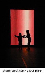 Silhouettes of two children dancing in front of a red light art installation at Nuit Blanche, which translates to 