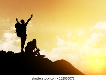 Silhouettes of two hikers with backpacks enjoying sunset view from top of a mountain - Shutterstock ID 132056078
