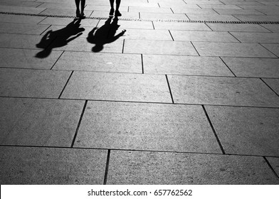 Silhouettes Of Two People Walking By The Street, Black And White