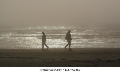 Silhouettes Of Two Persons Walking In An Opposite Directions On A Tillamook Beach, Oregon