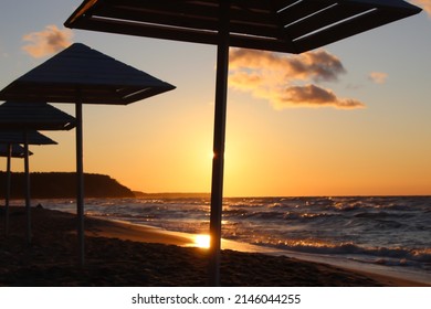 Silhouettes of wooden beach umbrellas on wet sand in stormy weather at summer sunset  - Powered by Shutterstock