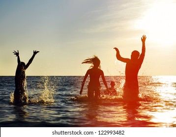 Silhouettes of young group of people jumping in ocean at sunset - Powered by Shutterstock