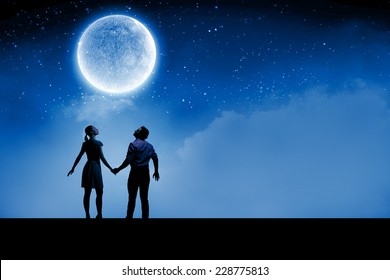 Silhouettes Of Young Romantic Couple Standing Under The Moon Light