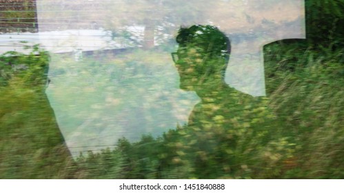 Silhouettes of young unrecognizable men passengers reflected in train window with green landscape passing by. Ecologic transport, environment sustainability, eco planet save earth creative concepts. - Powered by Shutterstock