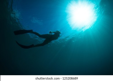 Silhouettes Of A Young Women Free Diving In The Pacific Ocean