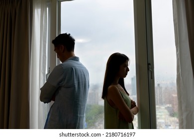 silhoutte of asian couple has a serious argue in front of the window at home - they turn around face another side against each other