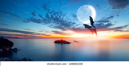 Silhoutte of beautiful dolphin jumping up from the sea at sunset with super moon "Elements of this image furnished by NASA "