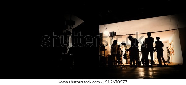 Silhoutte images of video production and\
lighting set for filming which movie crew team working and\
silhouette shadow of camera and professional equipment in big\
studio for commercial\
advertising.