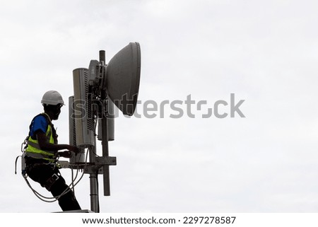 Silhoutte of man assembling an antenna and sensors in the communications industry