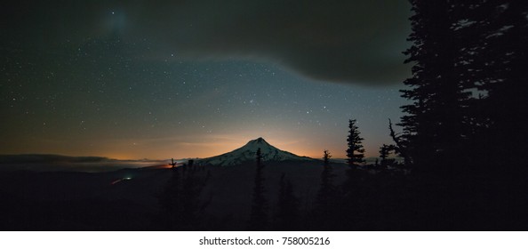 Silhoutte Of Mt. Hood At Night With Glow Of Portland In Distance