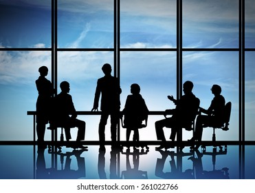 Silhouttes Of Business People As Team Sitting Round Table