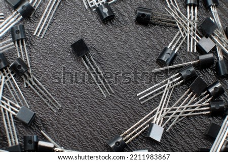 Silicon transistors scattered on a workbench. Blank generic PNP or NPN transistors. Electronic components