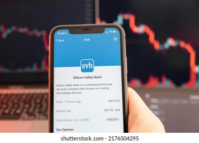 Silicon Valley Bank Stock Price Downtrend With Red Graphs On The Background. Man Hands Holding A Smartphone With Logo On The Screen, February 2022, San Francisco, USA. 