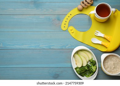Silicone baby bib, toy and plastic dishware with healthy food on light blue wooden, flat lay. Space for text - Shutterstock ID 2147759309