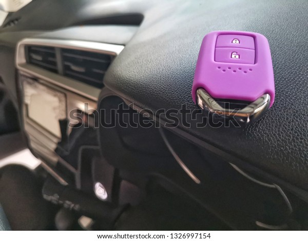 Violet​ silicone casing for remote car​ with​\
keys​  put​ on the​ car\
console.