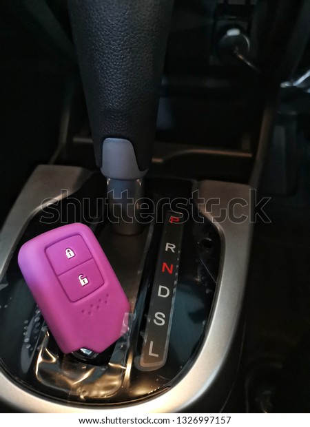 Violet​ silicone casing for remote car​ with​\
keys​  put​ on the​ car\
console.