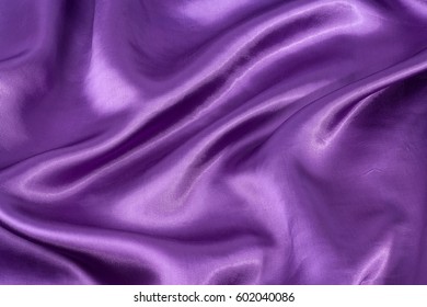 Silk background, texture of violet shiny fabric, close up