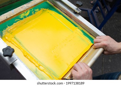 Silk Screen Print Process At Clothes Factory. Frame, Squeegee And Plastisol Color Paints.