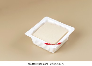 Silk Smooth Tofu or Tahu Sutra on Plastic Supermarket Packaging. Isolated on Cream Background 