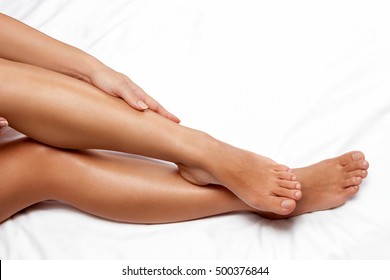 Silky smooth female legs on white sheet