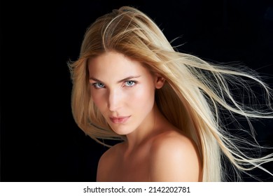 Silky strands in the wind. A beautiful young woman posing in front of a black background with the wind blowing through her hair.