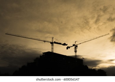 Sillhouette Of Building Construction With Two Crane On Morning Yellow Sky