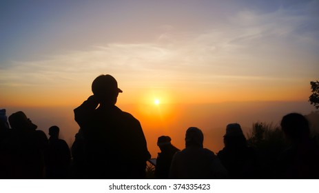 Sillhouette man and woman are looking to the sunrise on the mountain
