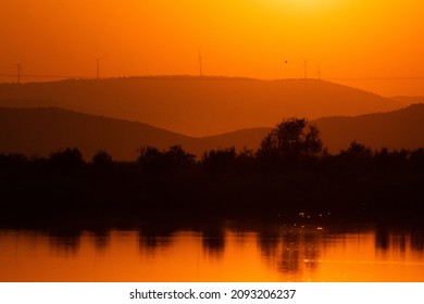 Sillhouette Of Trees And Mountains At A Lagoon Under Sunset In Greece