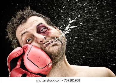 silly boxer man takes a punch in the face isolated on black.funny concept portrait