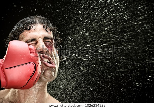 silly boxer man takes a punch in the face\
isolated on black.funny concept\
portrait