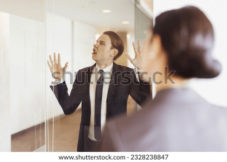 Silly businessman pressing face against office glass