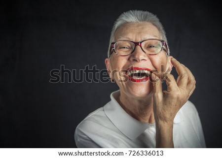 Silly childish elderly senior lady pulling pranks, zipping her mouth shut