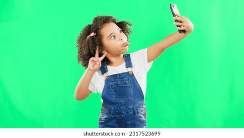 Silly little girl, selfie and peace sign on green screen with goofy facial expressions against a studio background. Female child or kid making funny face with hand sign for photo or vlog on mockup - Powered by Shutterstock