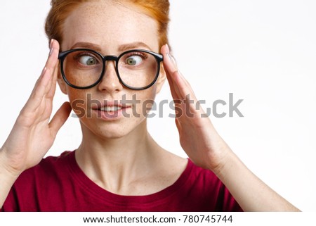 Silly redhead freckles woman smiling face and squinting eyes and touching glasses
