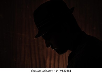 Silouette Portrait Of A Man With A Borsalino Type Hat, Mysterious Atmosphere, He Could Be An Investigator, The Man Is Serious And Looks Down