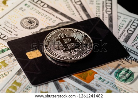 Silver bitcoin with credit card on top of dollars banknote background, new currency, accepting bitcoin for payment. Buy bitcoins online using credit or debit card concept.