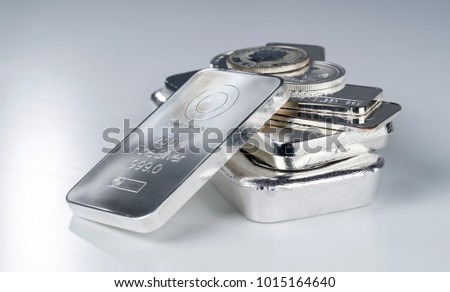 Silver bullion. Cast and minted bars and coins on a gray background. Selective focus.