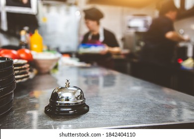 Silver Call Bell on table, chefs in a restaurant on background. cooking in the kitchen. - Powered by Shutterstock