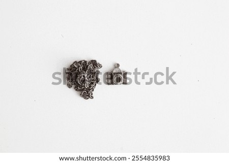 A silver camera charm designed with a nostalgic touch. Presented simply on a white background, this photograph symbolizes the longing for the past and the timeless magic of photography.