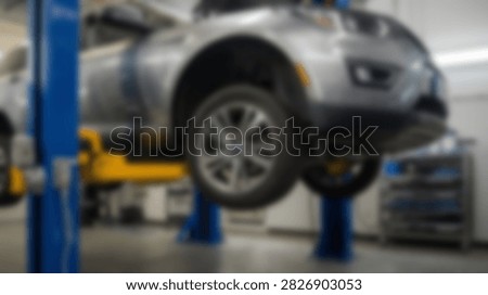 A silver car is elevated on a hydraulic lift for maintenance and repair in a modern auto service center.