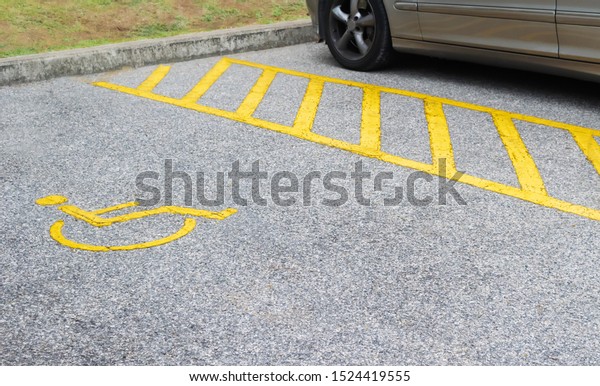 Silver car parking near handicapped parking sign\
area at asphalt parking lot, special car parking area for\
handicapped people only, transportation convenience for disabled\
people concept