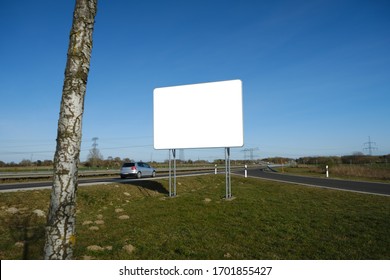 Silver Car Passing An Empty Mockup Billboard At A German Highway