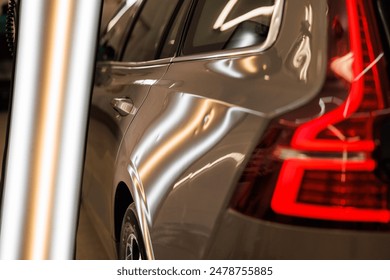 A silver car with a red brake light is parked in a garage with hail damage problems