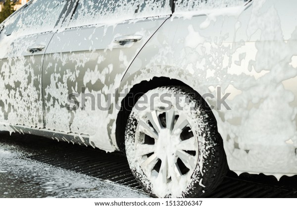 silver car in soap foam on the car wash.\
 Left\
wing and wheels.\

