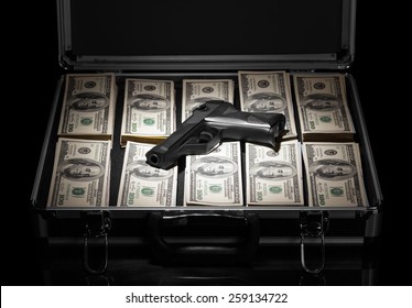 Silver case with money and gun on black background