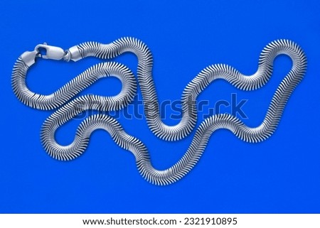 Silver chain necklace lying on blue studio background