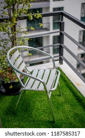 Silver Chair and small tree in back on grass balcony of condominium - Shutterstock ID 1187585317