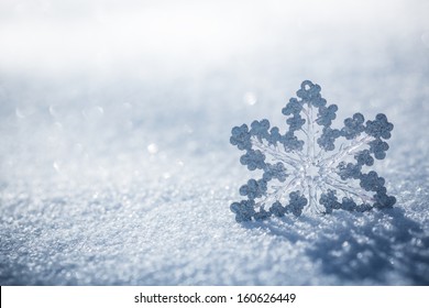 Silver Christmas decoration. Beautiful snowflake on real snow outdoors. Winter holidays concept