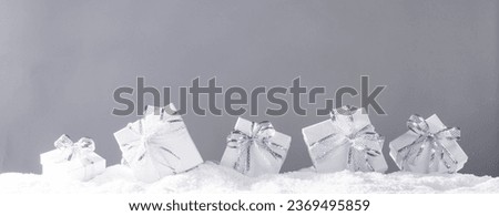 Silver christmas present gift boxes in a row on snow over gray background
